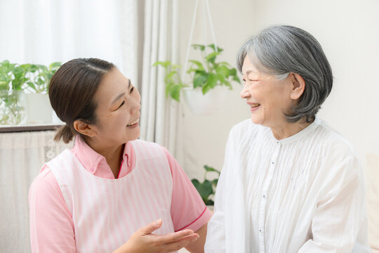訪問介護で高齢者と会話するホームヘルパー、在宅介護、見守り、コミュニケーション、笑顔で寄り添う見つめ合う女性介護職