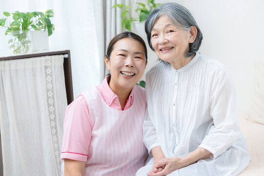 A home health aide conversing with an elderly person during a home care visit; home care, monitoring, communication; a female caregiver offering support with a smile; a female caregiver looking direct