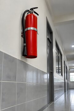 Red fire extinguisher mounted on a wall in a tuition centre corridor
