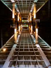 Obraz premium Symmetric architectural view of bridge structure at night with glowing lantern streetlights and metal girders in perspective