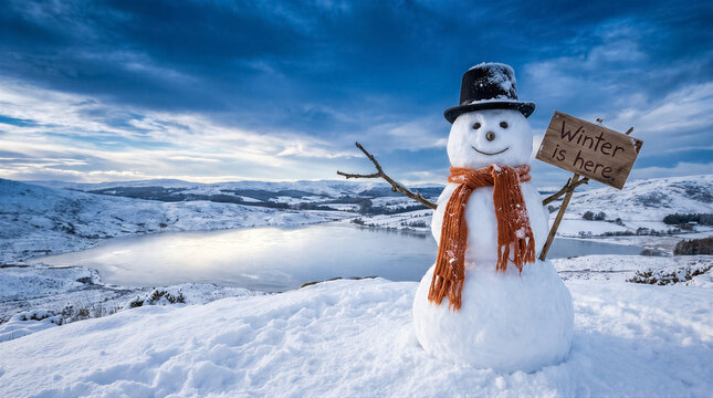A cheerful snowman wearing a hat and orange scarf holding a sign that says winter is here in a snowy mountain landscape