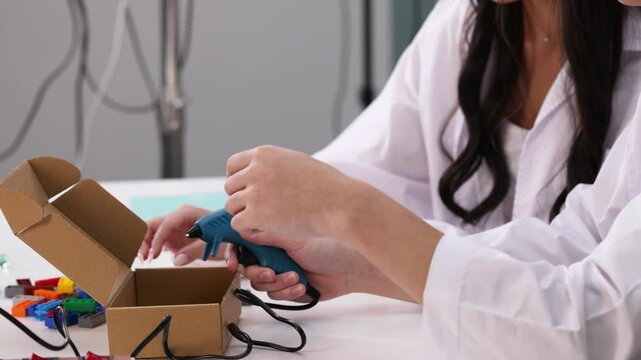 Teenager Using Hot Glue Gun for Science Project in Classroom