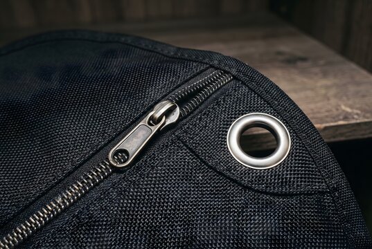 Close up of the zipper closure and metal hanger grommet of a nylon garment bag