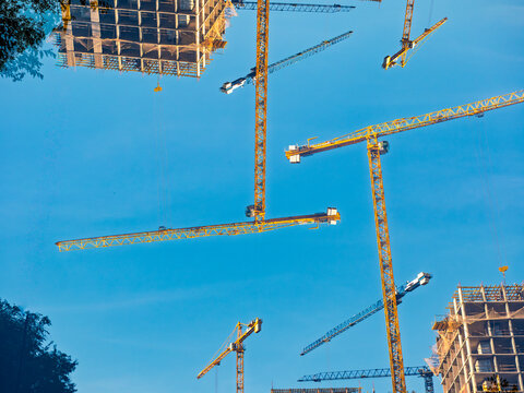 Abstract composition of construction cranes on blue sky background