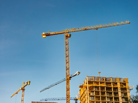 Modern construction site with yellow tower cranes against a clear blue sky