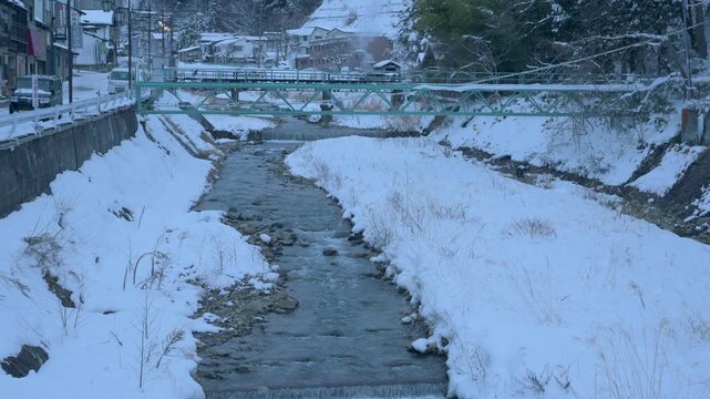 夕暮れのブルーアワーに染まる雪景色の渋温泉と川にかかる橋のスローモーション