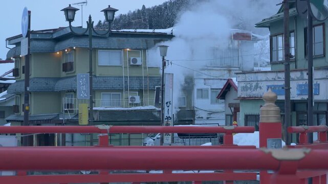 雪が積もる屋根と煙突から立ち上る白い湯気のスローモーション