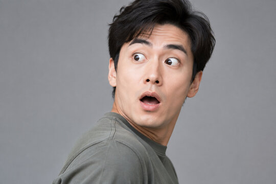 Surprised adult with wide eyes on gray background, shock and unexpected news concept