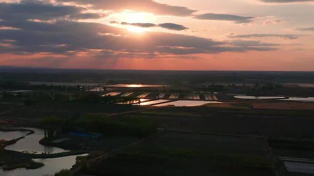 Aerial view of Xinjiang agricultural farmland at sunset with dramatic fire clouds and irrigation ponds
