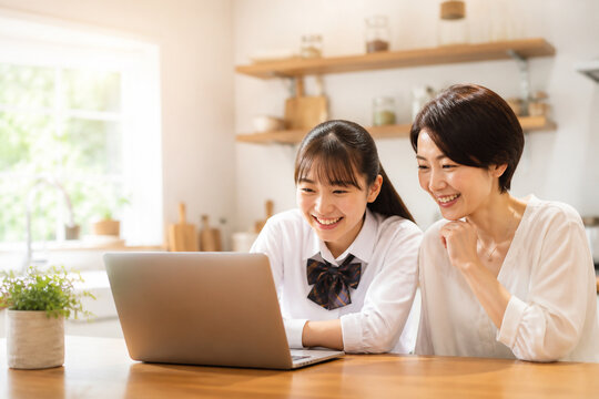 自宅でノートパソコンを見る母親と娘