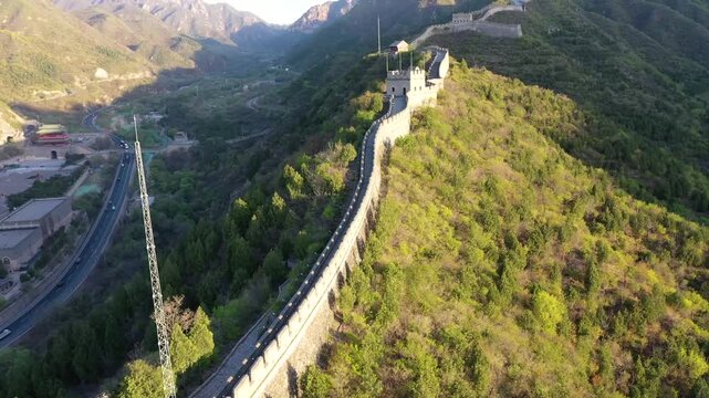 Great Wall of China at Juyongguan Pass winding through forested mountains at golden hour, aerial drone view