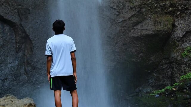 Rear View of Young Man Standing in Front of Curug Cimahi Waterfall in West Java
