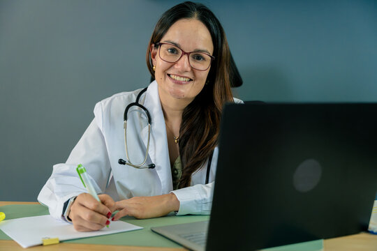 Female doctor writing prescription at desk smiling