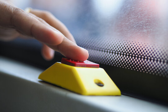Person presses button on bus to signal stop during daytime journey