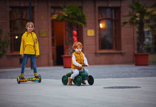 Two children having fun riding toy vehicles together outdoors