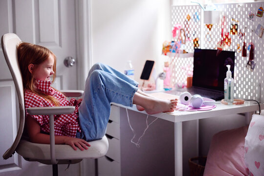 Happy girl relaxing at computer desk in cozy bedroom after school
