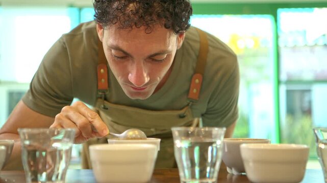 Coffee professional carefully tasting brewed coffee samples during a sensory cupping session, using a spoon to evaluate flavor and quality across multiple cups