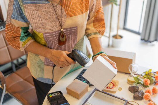 Mature Asian woman using barcode reader scan handcrafted jewelry package