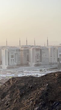 Panoramic view of the sacred Medina skyline and historic mosque from a rocky mountain vantage.