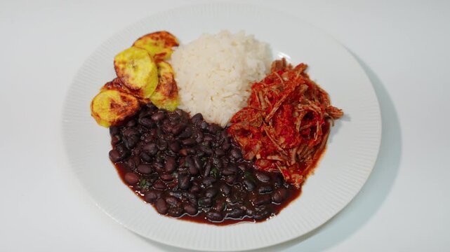 Pabellon criollo serving shredded beef, black beans, white rice, and fried plantains, a traditional venezuelan meal.