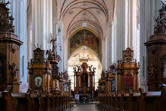 Vilnius, Lithuania &ndash; The stunning historic interior of the Bernardine Church, showing intricate wooden altars, Gothic arches, and religious artwork inside the nave.