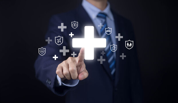 Businessman touching a glowing medical cross with insurance shields, symbolizing health insurance, healthcare protection, family security, risk management, medical coverage, and financial protection.