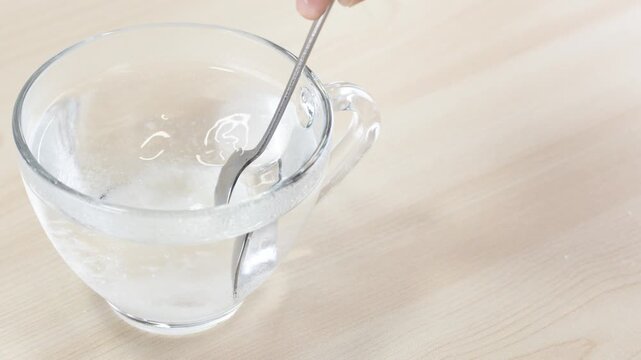 Stirring Sugar into Water with Spoon in Glass Cup