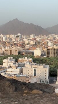 High-angle view of Medina cityscape, palm trees, and Masjid Al Fath minaret.