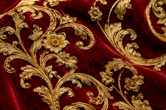 Intricate gold filigree patterns on red velvet, rich contrast texture study.
