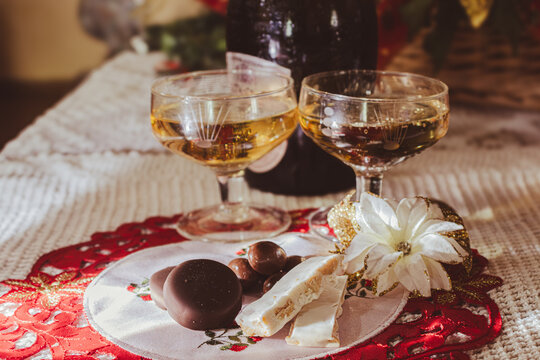 Christmas Eve celebration with two champagne glasses, turron and chocolates on a festive table setting, symbolizing holiday cheer and tradition