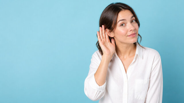 Attentive woman in a white shirt cups her ear while listening beside empty copy space on a cyan background.