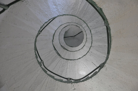 Interior staircase of a lighthouse, featuring elegant curves and an illuminated metal structure that reveals striking architectural details and evokes the classic atmosphere of coastal navigation.