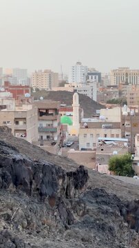 Panoramic view of Masjid Al Fath minarets and Medina city landscape from a rocky hill.