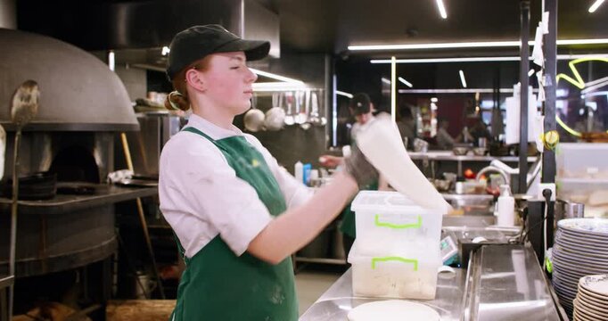 Tossing dough. Pizza chef. Young skilled female hand stretching wheat base spinning in kitchen italian traditional cuisine restaurant.