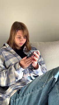 Teenage girl relaxing on couch with smartphone, everyday tech, screen habit