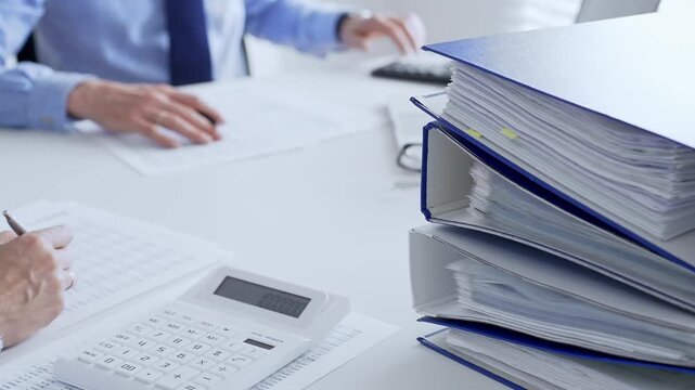 Accountants collaborating on financial reports and strategies while calculating and verifying documents in an office setting. Audit and taxes in business