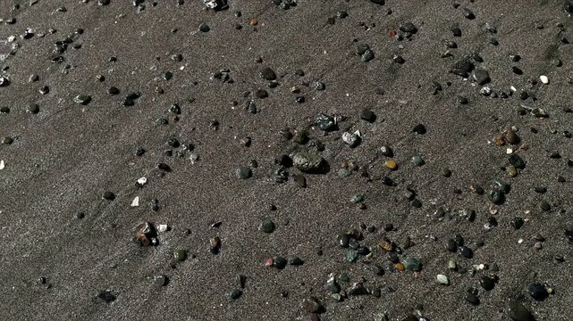 Scenic close-up of a rocky sandy beach in Japan with small colorful stones and shell fragments. Minimal nature background for coastal travel, texture and summer vacation themes.