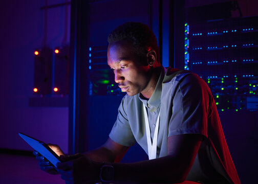 Cybersecurity Technician Working with Tablet in Data Center
