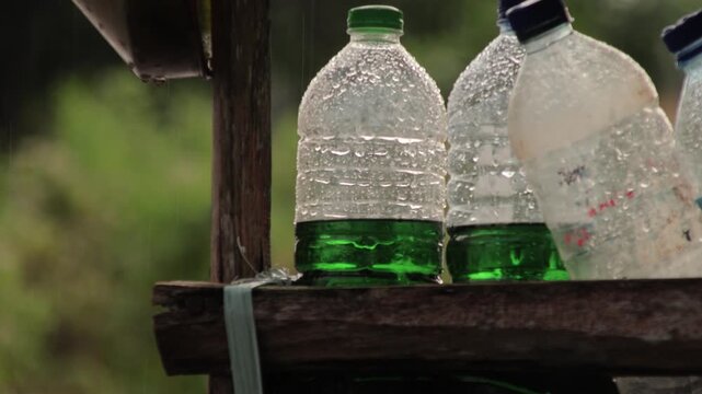 Plastic bottles with green fuel on wooden shelf in the rain