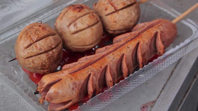 Grilled Meatballs and Sausage on Skewers with Chili Sauce in Plastic Container