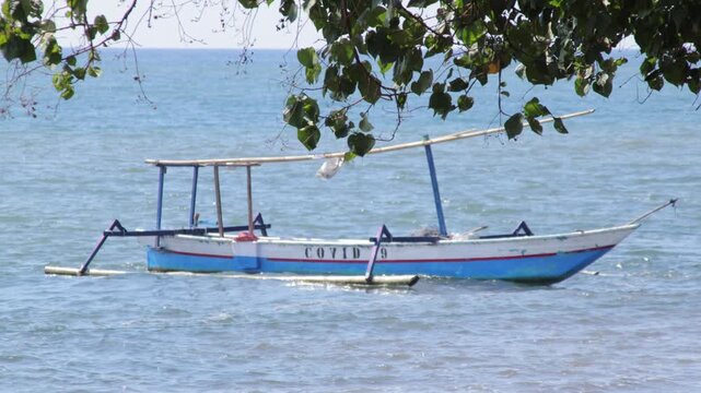 Indonesian Fishing Boat with COVID 19 Text on Blue Ocean
