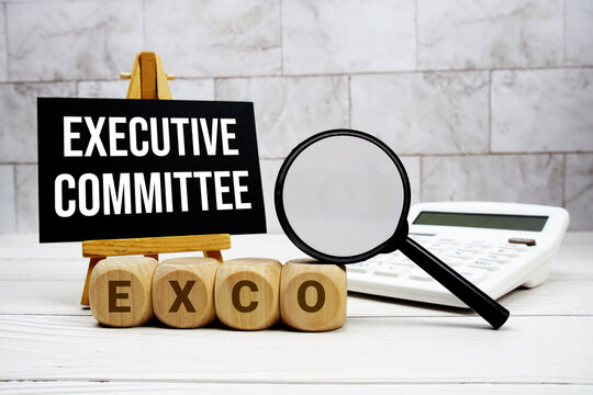 EXCO Executive Committee text with calculator magnifying glass and on wooden background