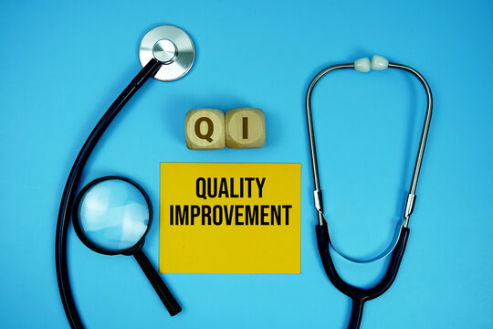 Quality Improvement (QI) text with stethoscope and magnifying glass on blue background