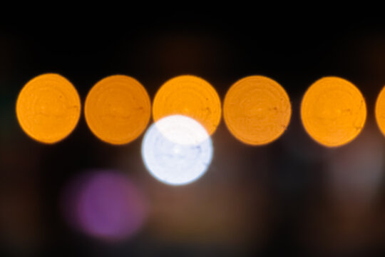 Row of Orange Bokeh Circles with Single White Light on Dark Background