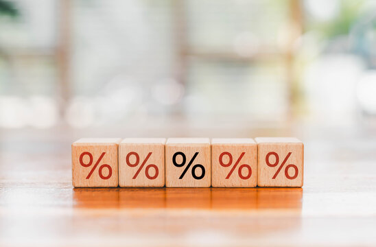 Financial percentage concept with wooden blocks, interest rates, discounts, tax, finance, investment, savings, banking, pricing, business economics, and financial planning in a bright office setting.