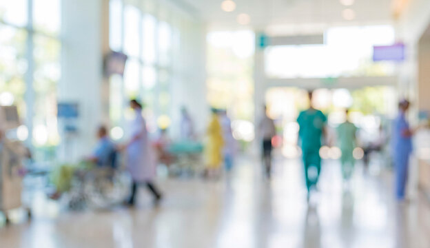 A blurred view of healthcare professionals walking through a modern hospital corridor, showcasing the busy environment that supports patient care and healthcare services.