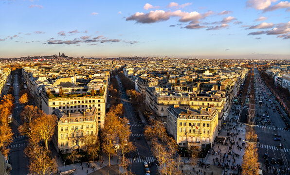 Panoramic aerial view of Paris cityscape and Champs-Elysees avenue during golden hour sunset with Sacre-Coeur basilica in the background, France.