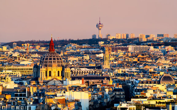 Paris cityscape at sunset featuring Saint-Augustin Church, Romainville TV tower and classic rooftops under a warm golden sky