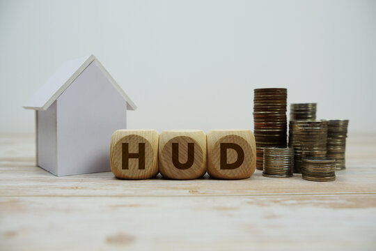 HUD (Department of Housing and Urban Development) text with house model and coin stack Properties and Real Estate Concept