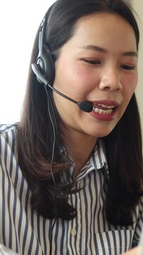 close up scene asian woman call center agent wear headset device and smiling working in operation room with service-mind at desktop table , telemarketing and help desk concept